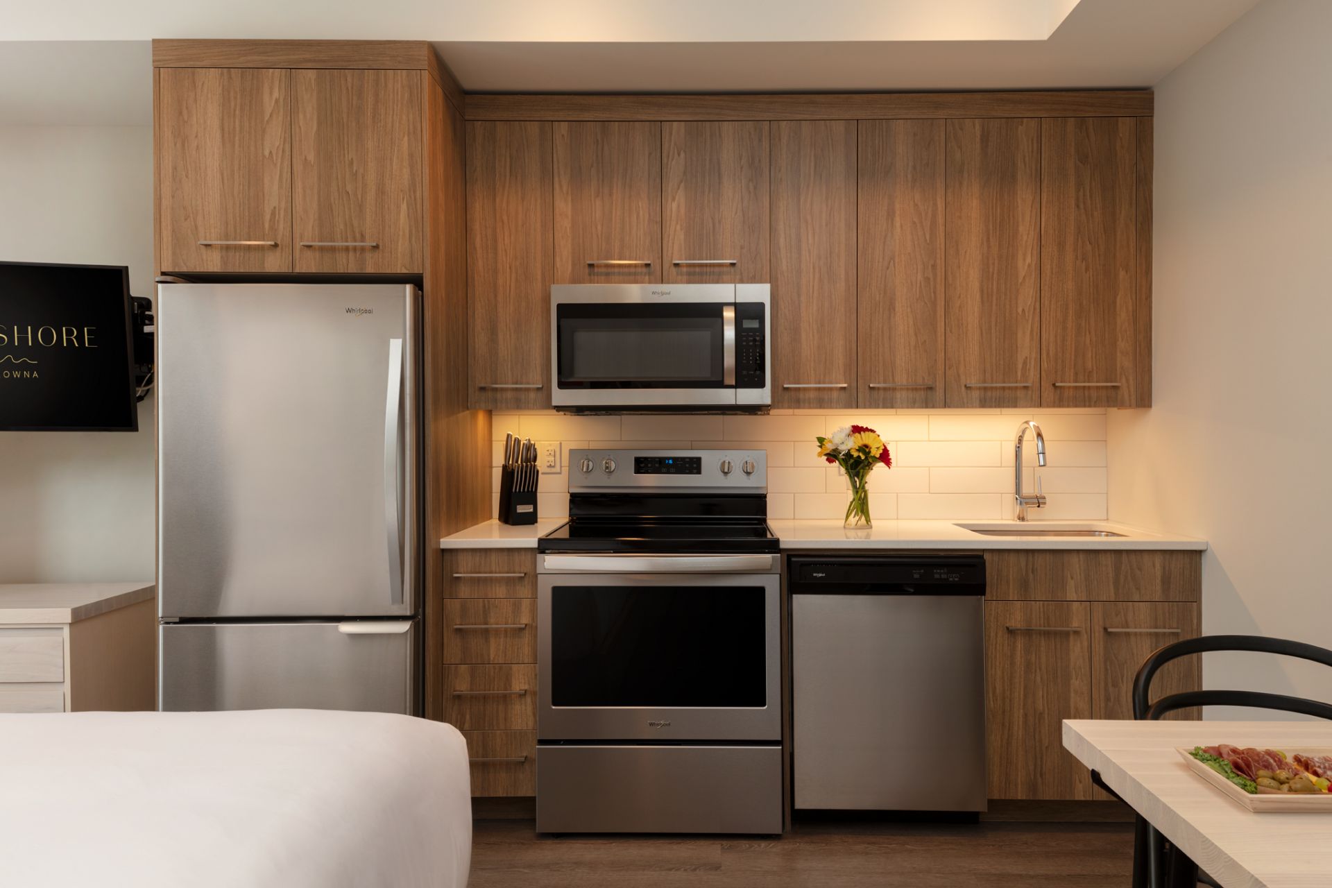 the kitchen of the studio suite at The Shore Kelowna, with stainless steel appliances and wood cabinets