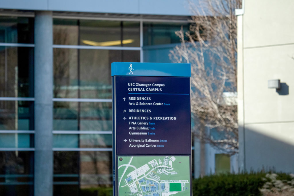 a close up of a sign board at the university of british columbia okanagan, with a map of the campus and arrow guides to different buildings on campus