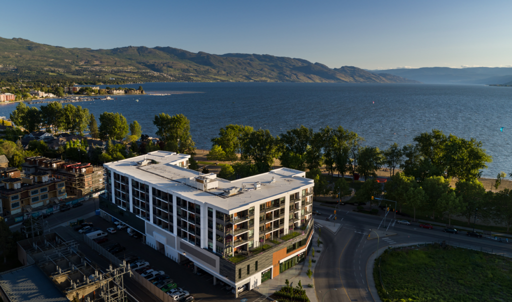 the shore kelowna, a birds eye view with the lake, gyro beach and mountains in the background